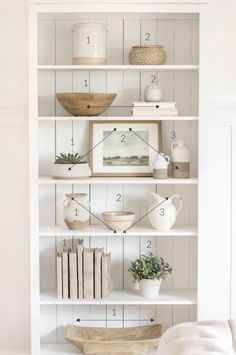 a white book shelf filled with books and vases