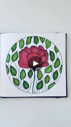 an open book with a drawing of a red flower on the cover and green leaves around it