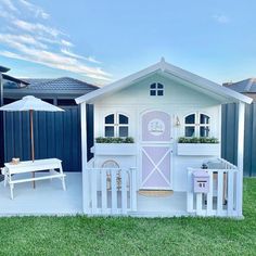 there is a small white house with a pink door