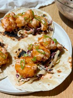 three shrimp tacos on a white plate