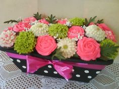 a black box with pink, white and green flowers in it sitting on a table