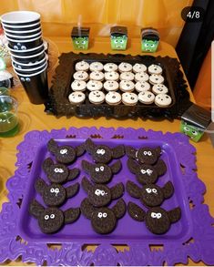 there are many cookies and cupcakes on the purple tray at this halloween party