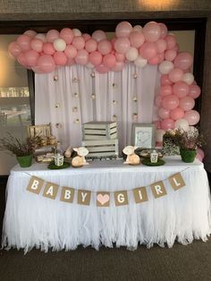 a baby shower table with pink and white balloons