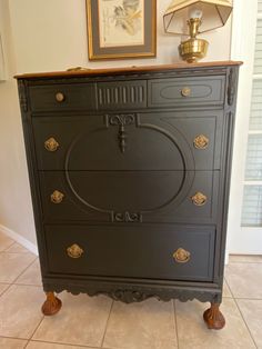 an antique dresser painted black with gold details