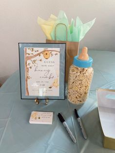 baby shower items displayed on blue table cloth with gift bag and note card in glass jar