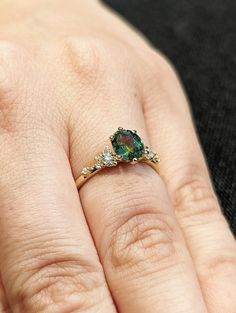 a woman's hand with a ring on it and a green stone in the middle