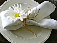 a white plate topped with a napkin and a flower