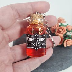 a hand holding a small bottle of emergency period syrup with flowers in the back ground