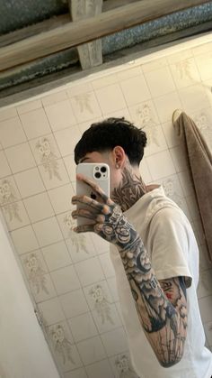 a man taking a selfie in the mirror with his cell phone and tattoos on his arm