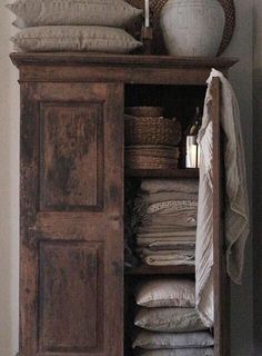 an old wooden cabinet with linens and pillows