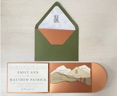 an open envelope with a card inside and a gold foil stamp on the front, featuring a mountain scene