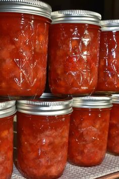 several jars filled with red liquid sitting on top of a shelf next to each other