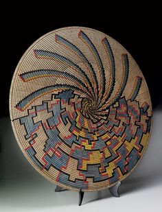 a basket sitting on top of a wooden stand next to a black object with an intricate design