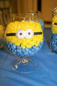 two glasses with candy in them are decorated like a minion and one has googly eyes