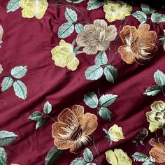 the fabric has flowers on it and is maroon with green leaves, yellow and brown