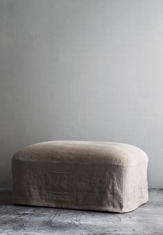 a large ottoman sitting on top of a floor next to a white wall in a room