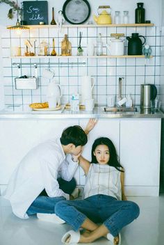 a man kneeling down next to a woman on the floor in front of a counter