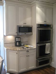 a kitchen with white cabinets and silver appliances