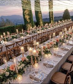 a long table is set up with candles and place settings for an outdoor dinner party