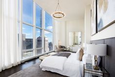 a bedroom with large windows and a white bed