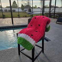 a watermelon blanket sitting on top of a chair next to a swimming pool