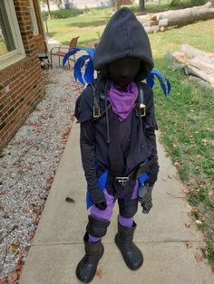 a young boy dressed in costume standing on the sidewalk