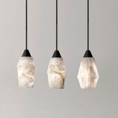 three light fixtures hanging from black cords in the shape of hexagonal shapes with marbled materials