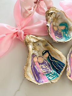 three clamshells with paintings on them and a pink ribbon tied around it