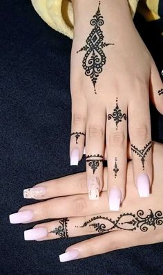 two hands with henna tattoos on them, one is white and the other is black