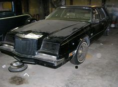 an old black car is parked in a garage