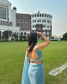 a woman standing on top of a lush green field next to a tall white building