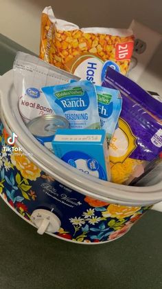 a close up of a bucket filled with food and snacks on a counter top next to a sink