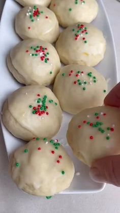 a person is picking up some cookies from a plate with sprinkles on it