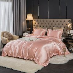 a bed with pink comforter and pillows in a room next to a window,