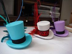 three hats with feathers are sitting on a table