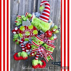 a christmas wreath hanging on the side of a wooden fence with green and red decorations