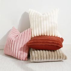 three pillows stacked on top of each other in front of a white wall and floor