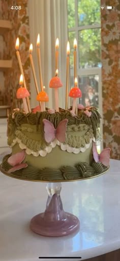 a green cake with candles on it sitting on a table