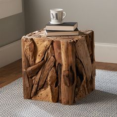 a coffee table made out of logs with a book on top and a mug in the middle