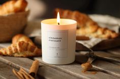 a candle sitting on top of a wooden table next to some croissants