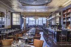 a restaurant with many tables and chairs in front of a bar filled with wine glasses