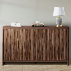 a wooden sideboard with a lamp on top of it next to a white wall