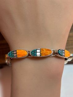 This is a beautiful, vintage, genuine Waldeck Jewelry multi stone and sterling silver bracelet that features natural blue turquoise, orange spiny oyster, and white Mother of Pearl / MOP. The bracelet is 7 inches.  The bracelet features 7 links each with the inlaid orange spiny oyster, rectangular-cut blue turquoise and white Mother of Pearl / MOP with black resin between the stones. Each link measures about 3/4" in length by a little more than 1/4" in width at the widest point. The stones are vibrant and the bracelet is very unique and well made. The bracelet is a little more than 1/4" in width at the widest point. It has some natural patina - a testament to its age - which its new owner can clean off if so desired. The bracelet weighs about 21.3 grams and is stamped 925 WJ, which is the h Sterling Bracelets, Black Resin, Jewelry Christmas, Spiny Oyster, Multi Stone, Blue Turquoise, Handmade Artisan, Chain Link Bracelet, Sterling Silver Bracelets