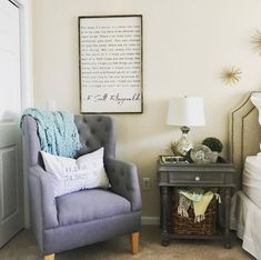 a bedroom with a gray chair and white bed