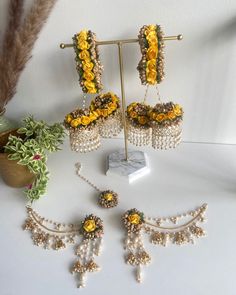 a collection of jewelry is displayed on a white surface with flowers and plants in the background