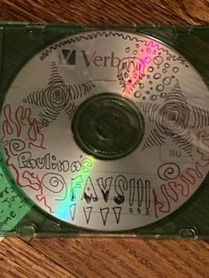 a cd with writing on it sitting on top of a wooden table next to a pair of scissors