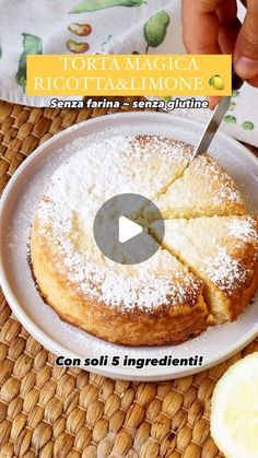 a person cutting into a cake on top of a white plate with lemon wedges