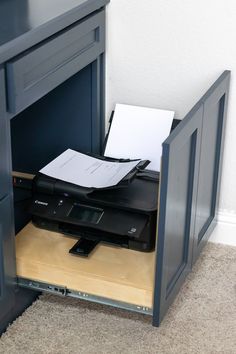 a desk with a printer on top of it and a paper sticking out of the drawer