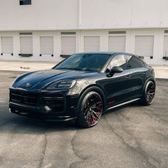 a black porsche cayen is parked in front of a building