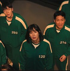 a group of people standing next to each other in green outfits with numbers on them